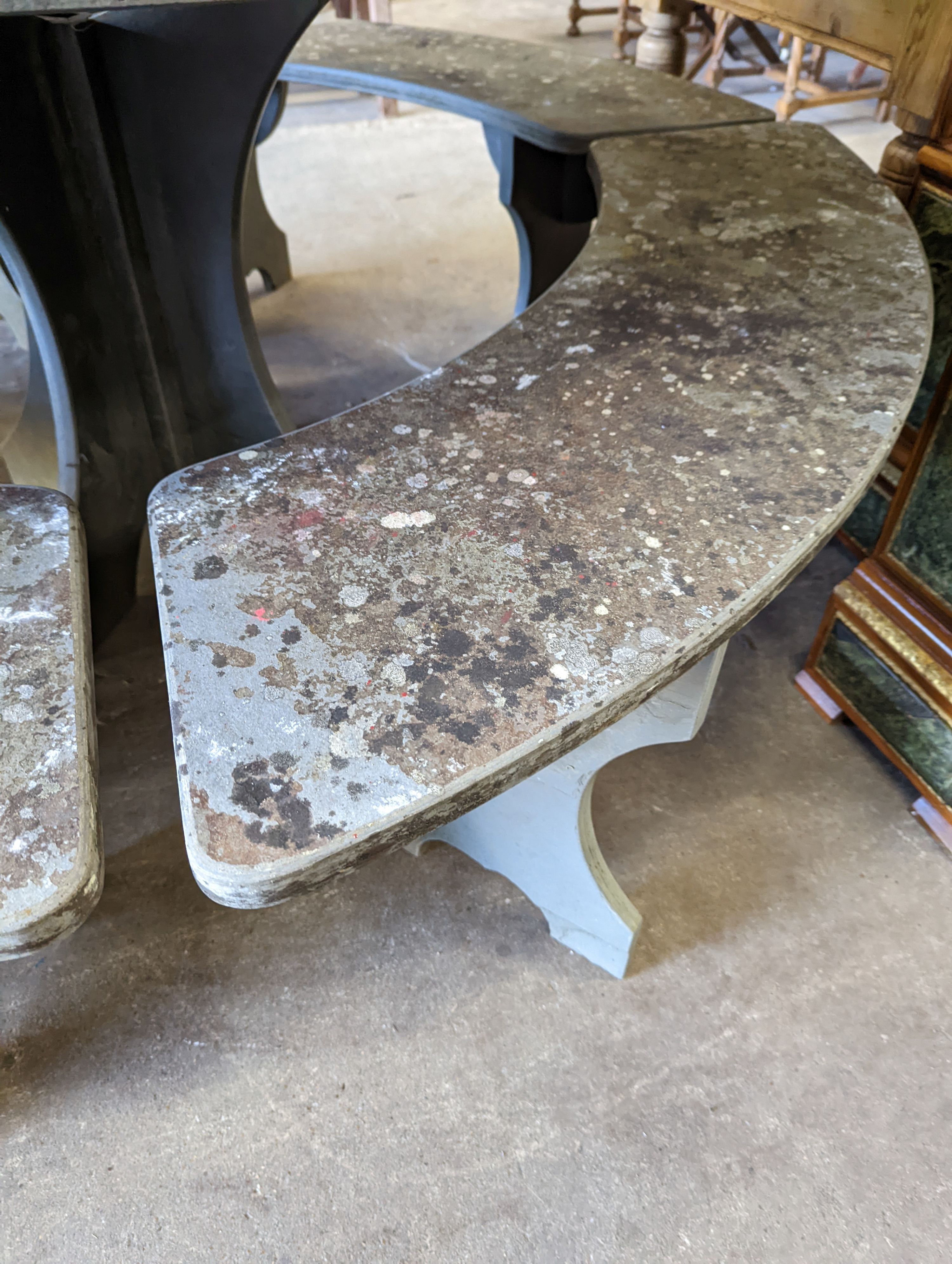 A heavy slate circular topped garden table, diameter 125cm, height 79cm together with four crescent shaped slate garden benches